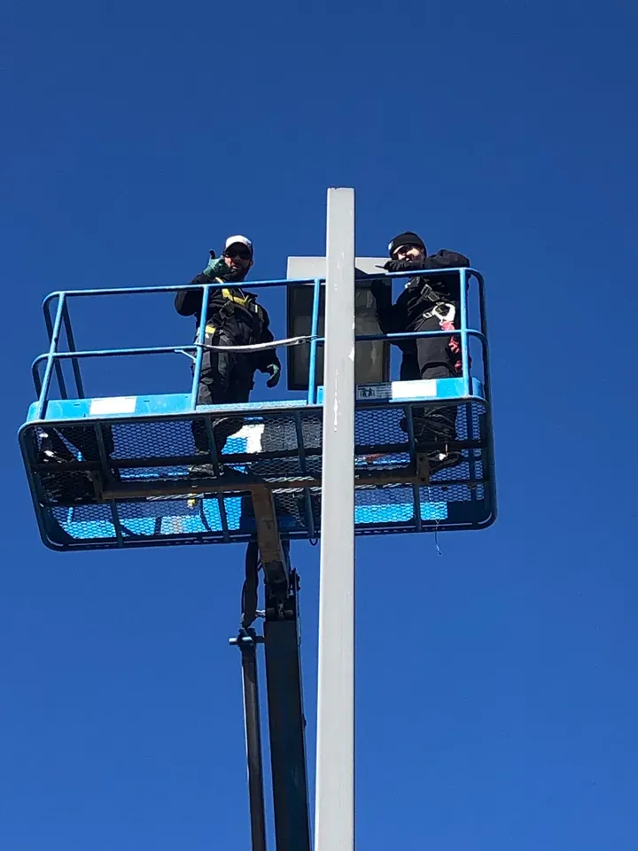 Electricians servicing a commercial parking lot light from a boom lift